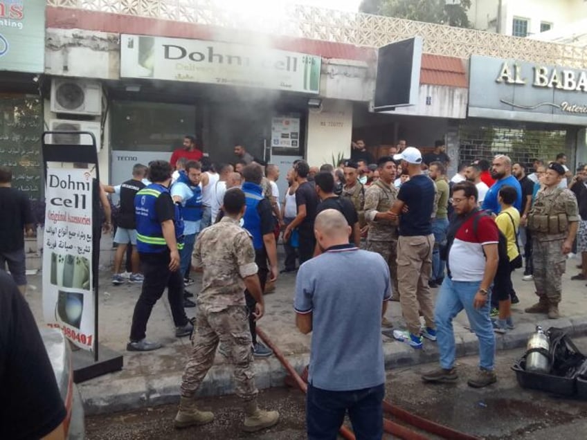 People and first responders gather at the scene of a reported device explosion in Saida in