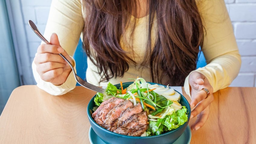 Woman eating steak.