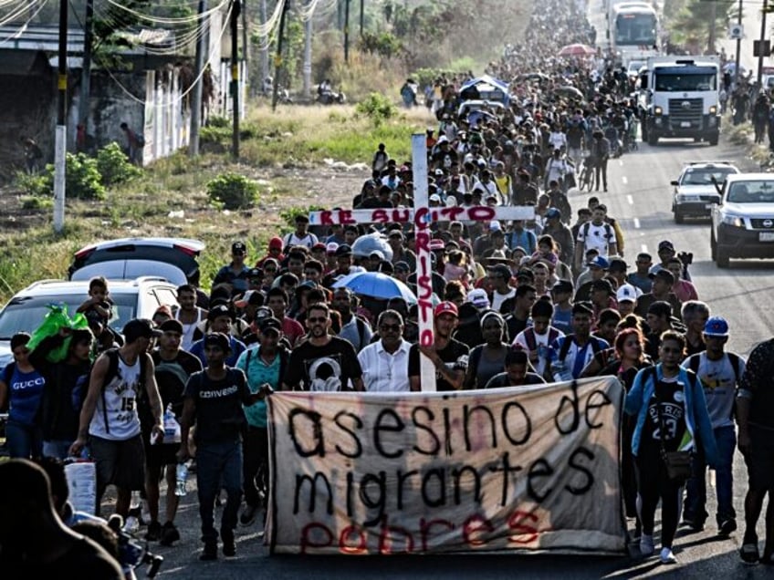 A group of migrants of different nationalities carry a cross leading a caravan that aims t