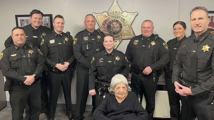 Sheriff's office posing with older woman.