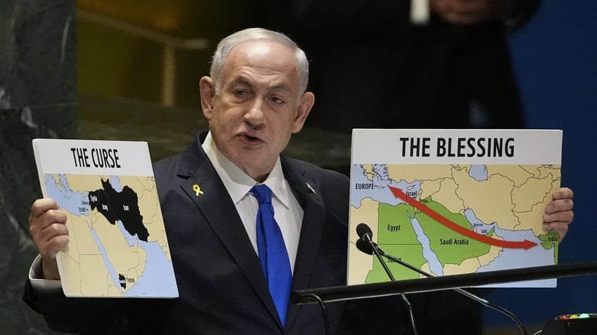 Israeli Prime Minister Benjamin Netanyahu holds signs as he addresses the 79th session of the United Nations General Assembly.