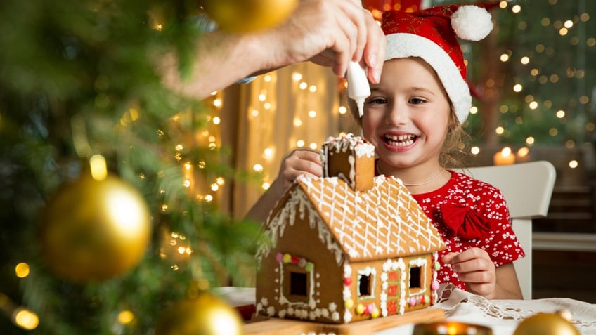 little girl decorating gingerbread house