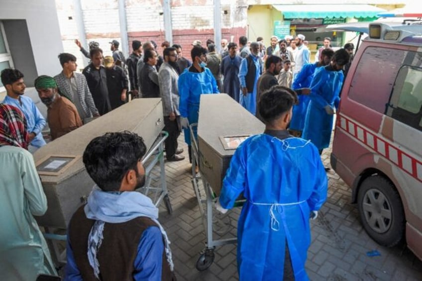 Paramedics carry slain migrant labourers' coffins at a hospital in Quetta