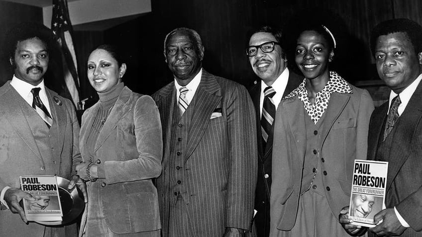 A group of men and women holding copies of 'Paul Robeson, The Great Forerunner' 