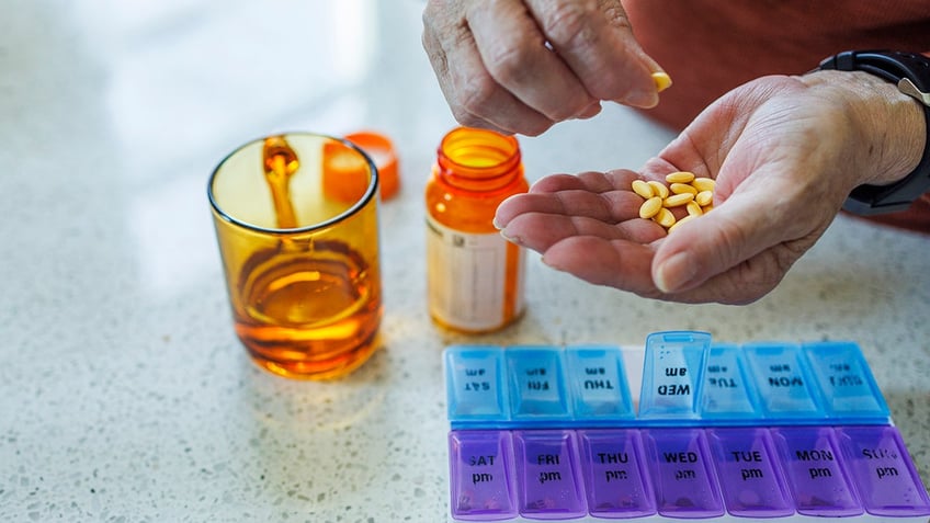 Close-up of hands organizing medication into daily pill organizer