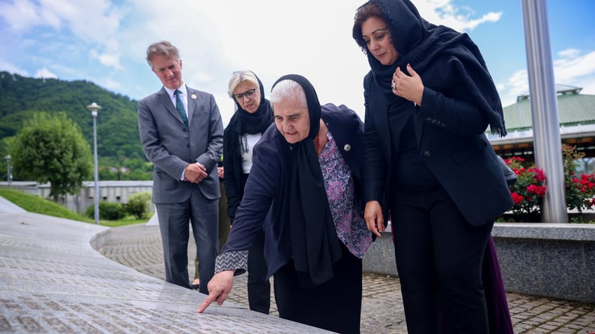 UK Minister of State (Minister for Europe) Nusrat Ghani, right, walks with Munira Subasic, president of the association Mother of Srebrenica, centre, next to the momument with the names of Srebrenica genocide victims, at the Memorial Center in Potocari, Bosnia.
