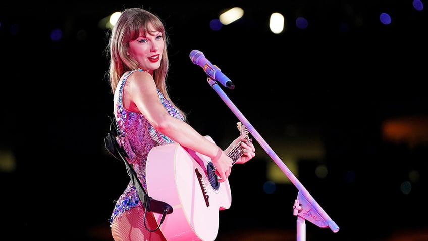 Taylor Swift playing guitar on stage