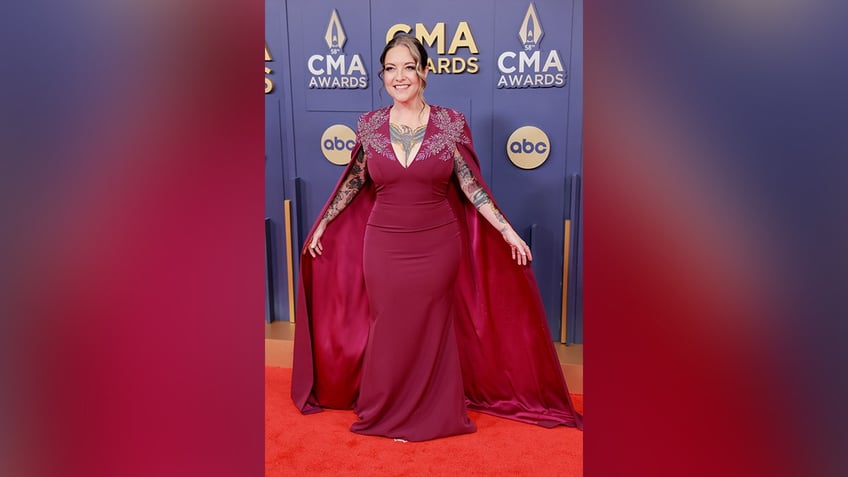 Ashley McBryde wore a red dress with a plunging neckline and a cape on the 2024 CMA Awards red carpet.