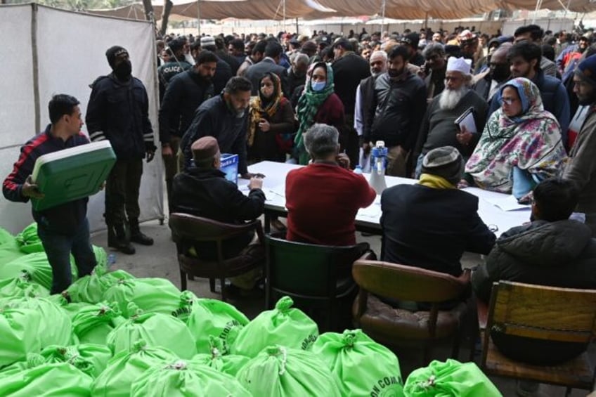 Returning officers wait to collect sacks of voting materials to polling stations from a distribution centre in Lahore, eastern Pakistan