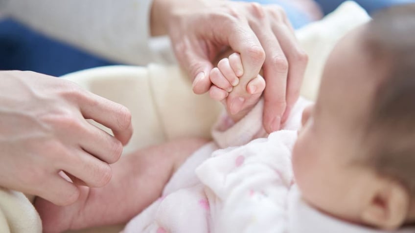 baby holding dad's finger