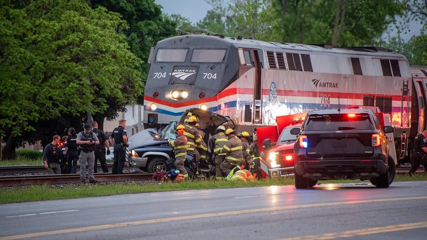 Emergency crews surround a crashed car on railway tracks