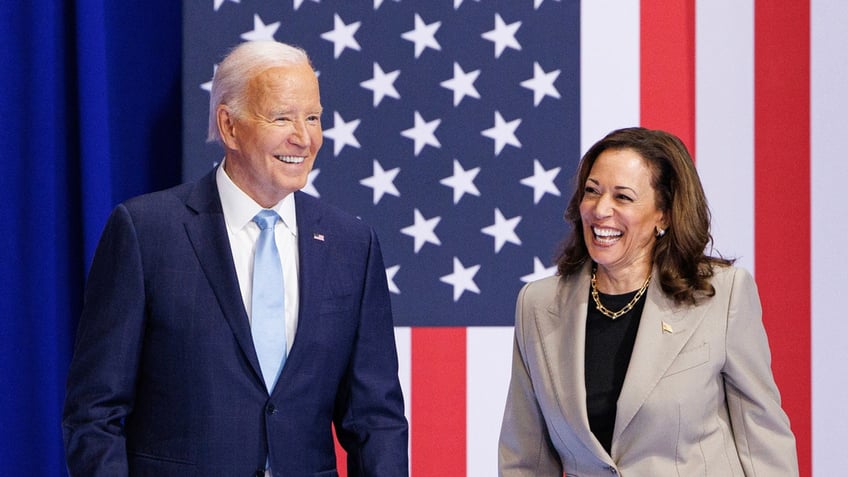 Joe Biden and Kamala Harris laughing with US flag behind them