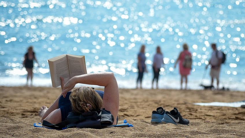Person reading book at the beach