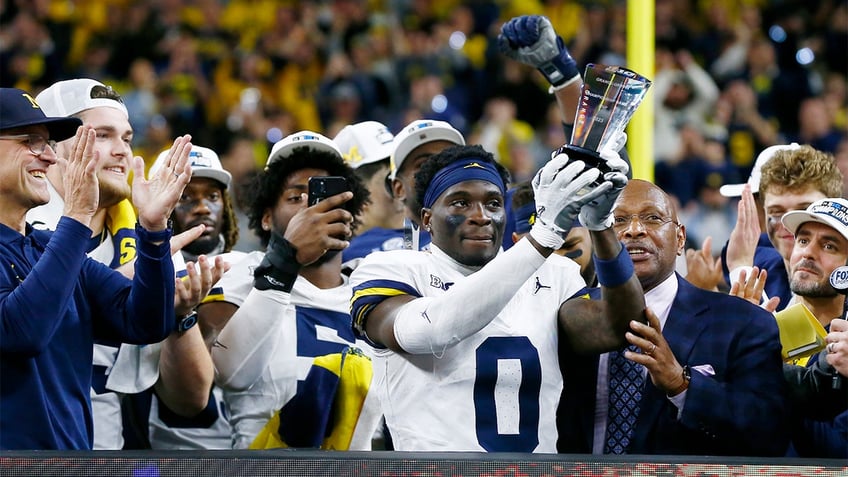 Mike Sainristil holds the Big Ten trophy