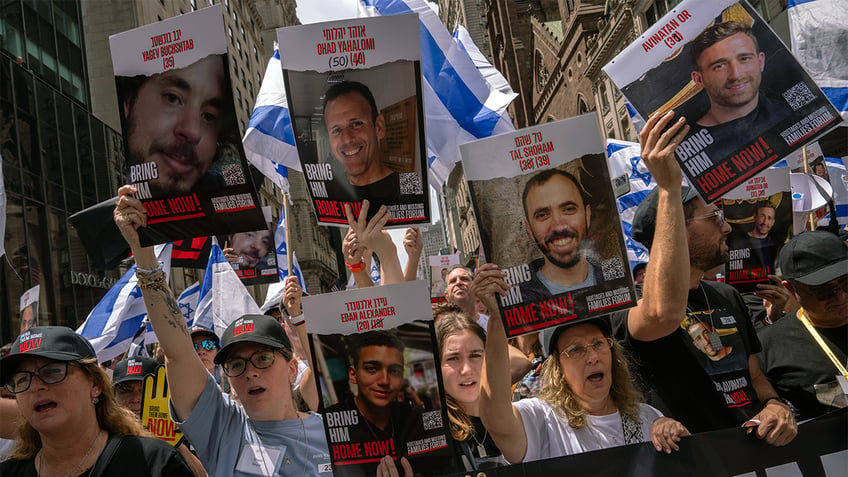 People, including the families of hostages, walk to the front holding "Bring them home now" signs at the Israel Day on Fifth parade on June 2, 2024 in New York City.