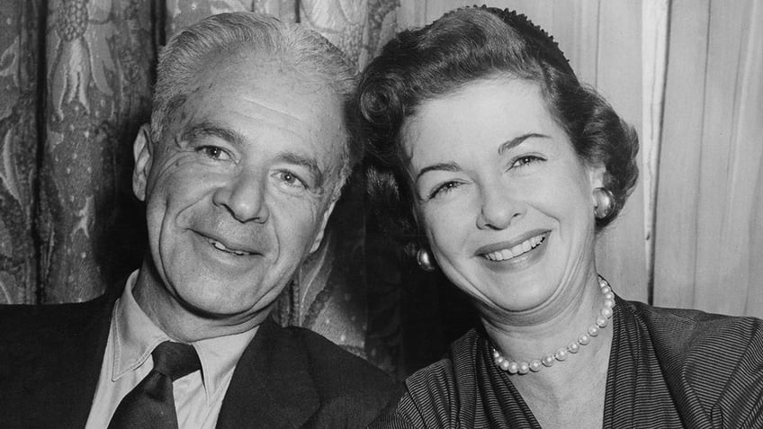 A close-up of Walter Wanger smiling with Joan Bennett wearing a dress and pearls.