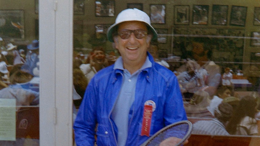 Jennings Lang in a bright blue jacket and pal blue shirt smiling