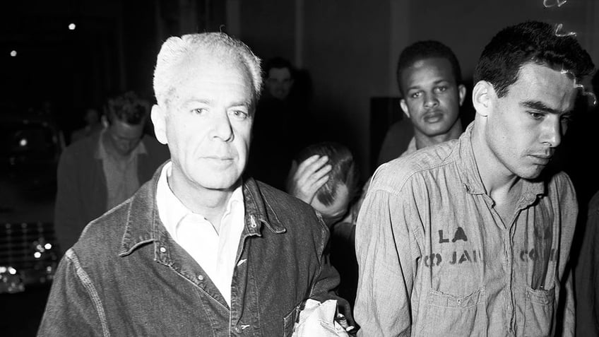 A close-up of Walter Wanger walking next to prisoners.