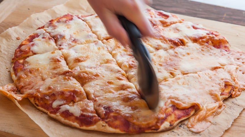 St. Louis Pizza being sliced into squares