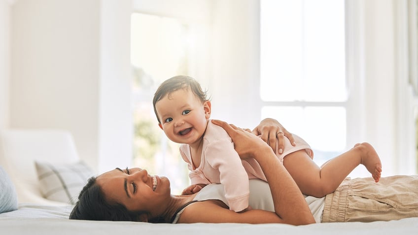 Mom and baby playing in bed