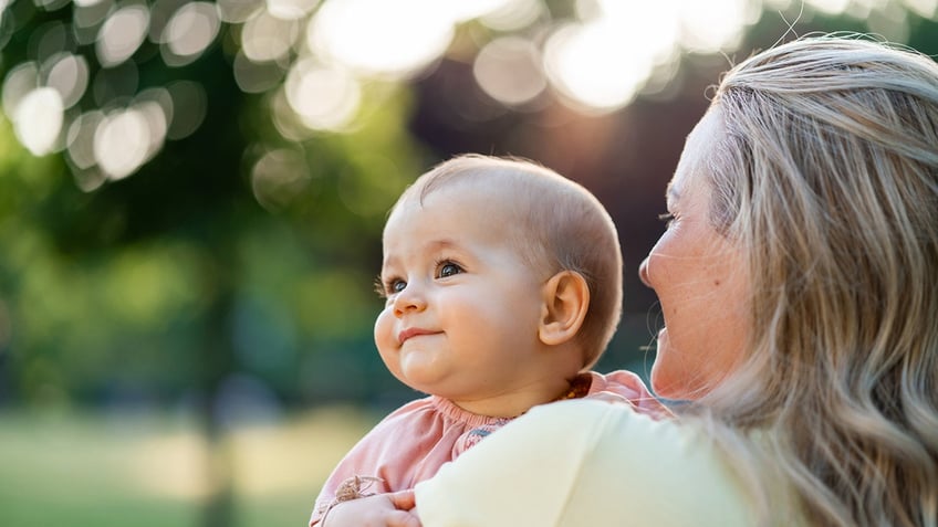 A mom holding her baby outside