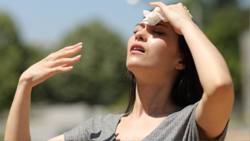 A woman wipes sweat form her head due to heat