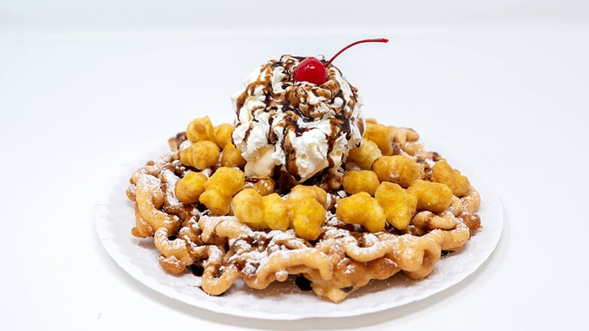 Funnel cake with ice cream on top and a cherry.