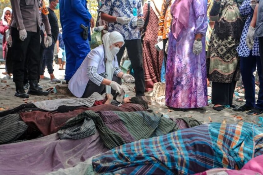 A medical official examines bodies of Rohingya refugees at a beach in Indonesia's Aceh Pro