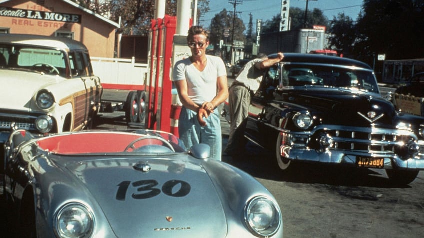 James Dean in front of his Porsche at a gas station