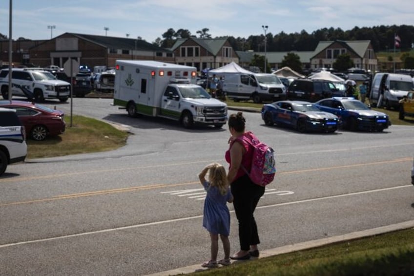 A girl and her mother watch as law enforcement and first responders surround Apalachee Hig