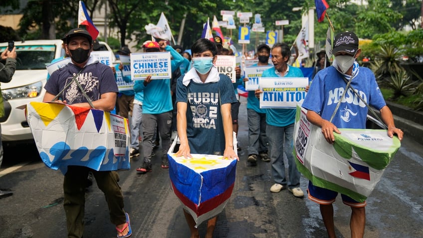 Filipino fishermen and activists wear colorful boat costumes, hold signs, and wave flags to protest against Chinese aggression in the disputed South China Sea at a rally in front of the Chinese consulate ahead of Independence Day.