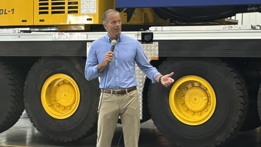 Sen. John Thune holding mic in front of heavy equipment