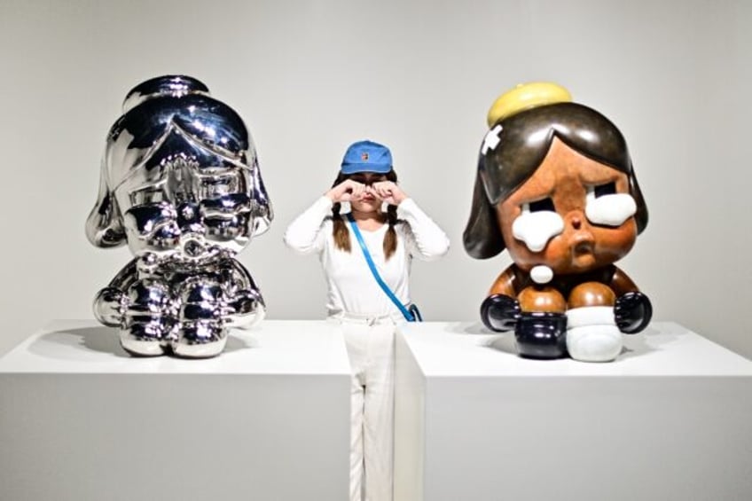 A visitor poses for photographs next to art sculptures, part of an exhibition titled "Everybody Cries Sometimes" by Thai artist Molly in Bangkok