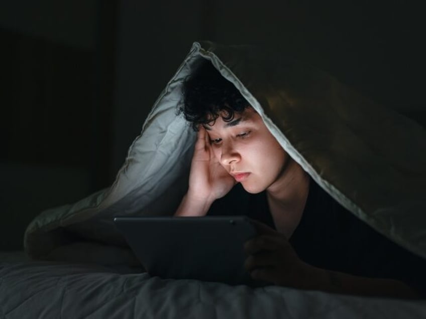 a boy using a tablet in bed