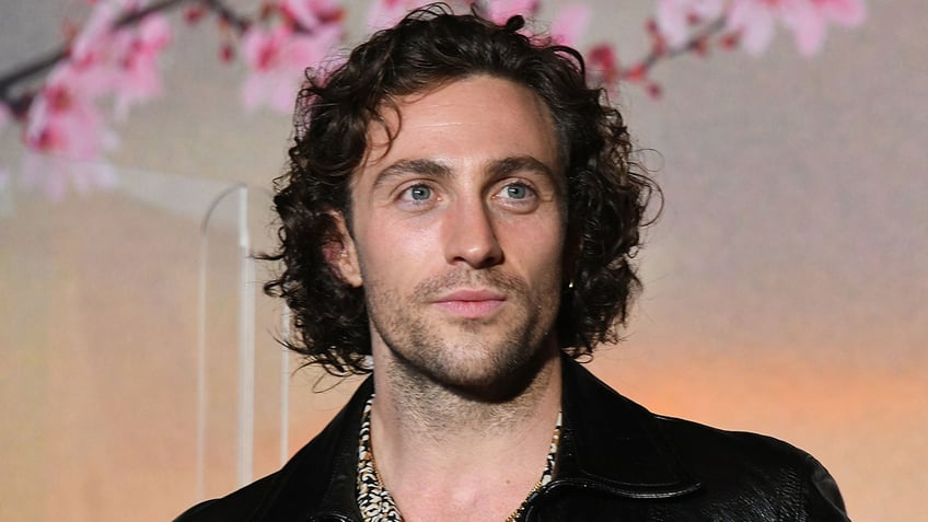 Aaron Taylor-Johnson looks to his left on the carpet in a black shirt