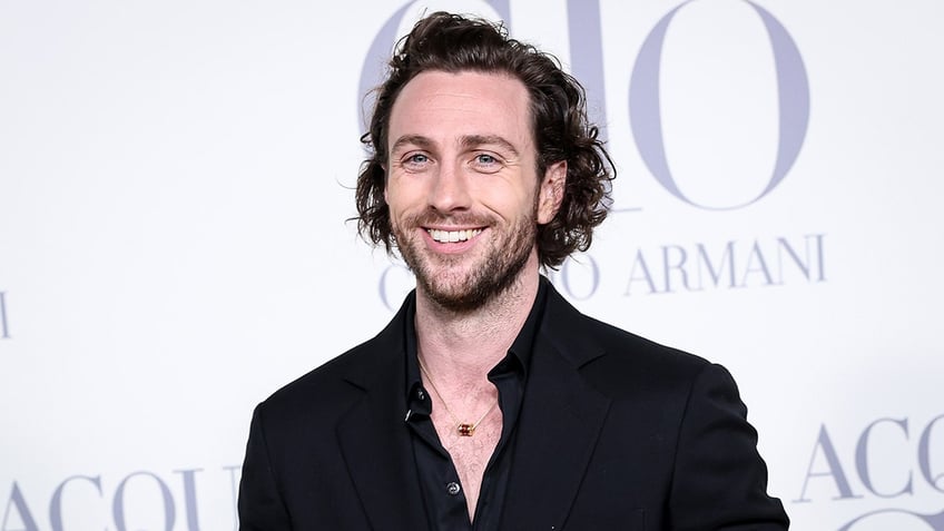 Aaron Taylor-Johnson in a black shirt smiles on the carpet in Spain