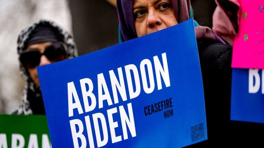 Demonstrators with the group "Abandon Biden" hold signs during a news conference prior to President Joe Biden's visit in Saginaw, Michigan, on Thursday, March 14, 2024.