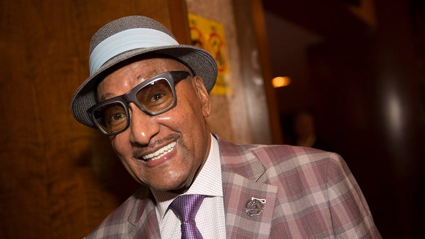 Four Tops singer Abdul Fakir smiles wearing plaid suit.