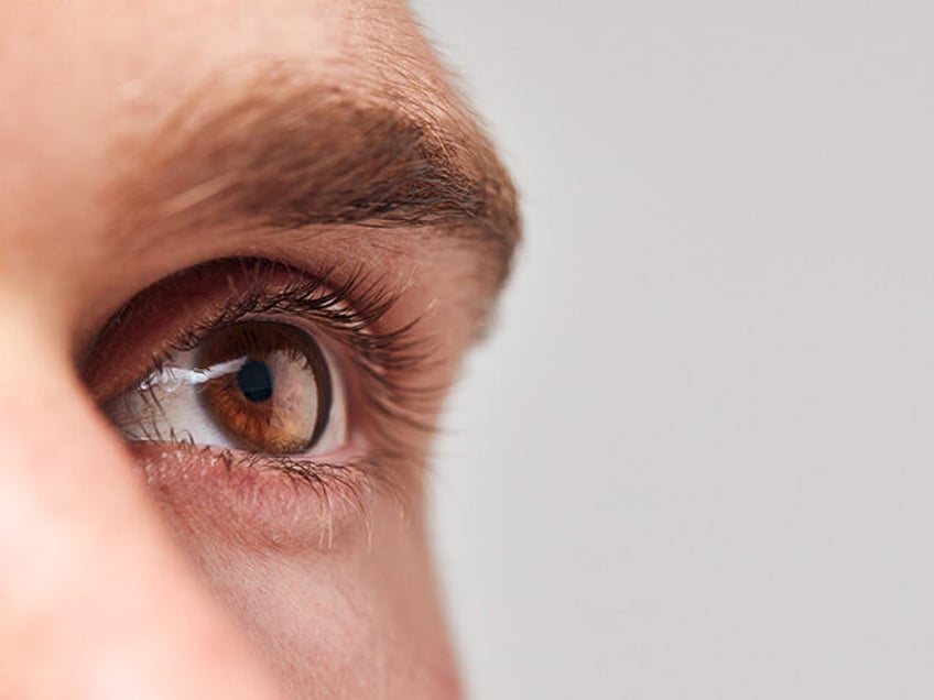 Extreme Close Up Of Eye Of Man Against White Studio Background