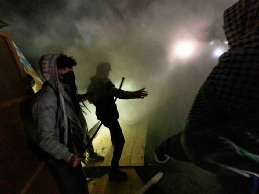 Pro-Palestinian demonstrators engulfed in tear gas regroup and rebuild the barricade surro