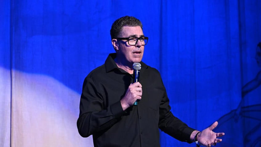 Adam Carolla on stage with a microphone