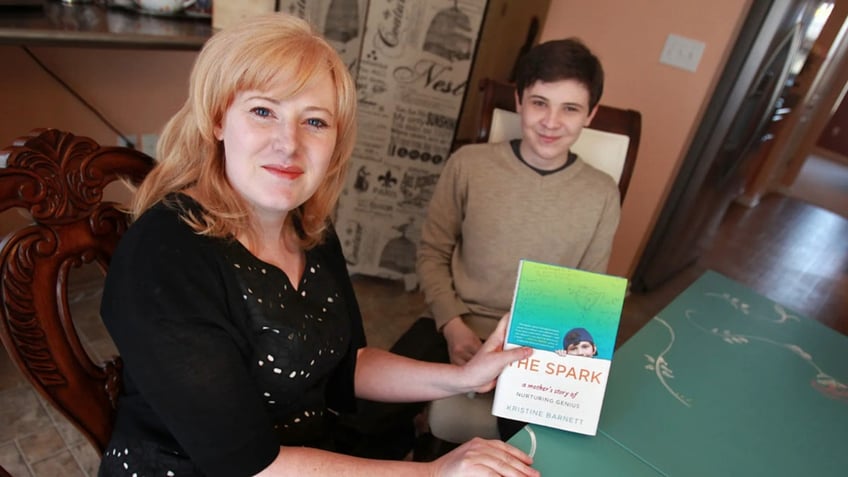 Kristine Barnett holding a book next to her son