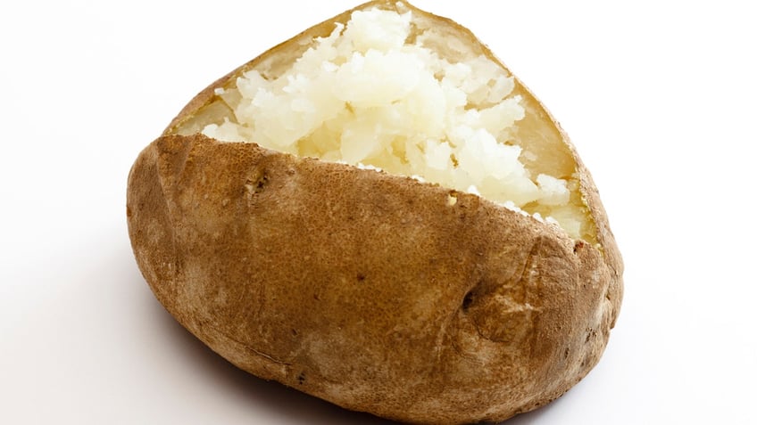 A baked potato is slit open with its skin exposed.