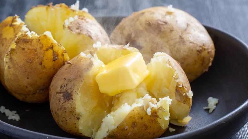 Baked potatoes are steaming with melting butter.