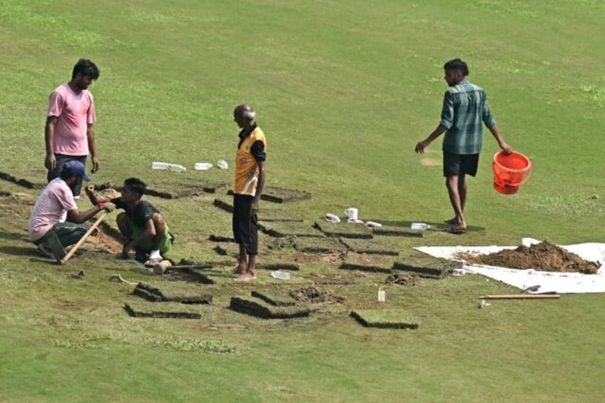 Groundsmen attempt to repair wet patches on the ground