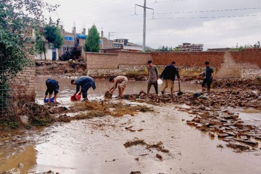 Afghans drain flood waters with shovel and buckets, after heavy rains on the outskirts of