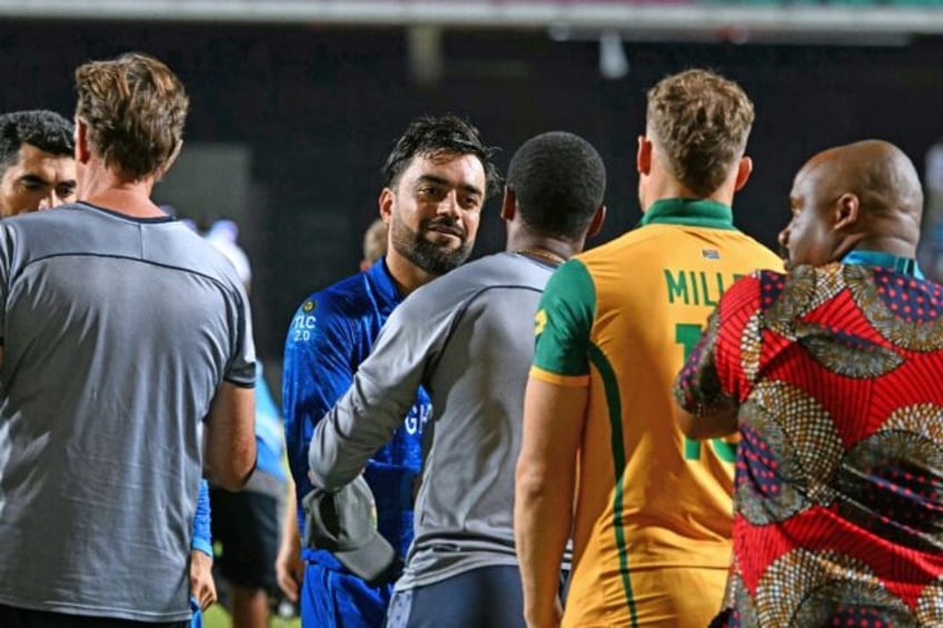 Afghanistan's captain Rashid Khan (centre) is consoled by South Africa's players after the