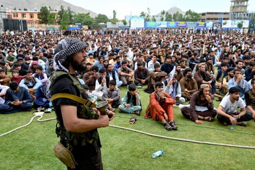 Afghan security personnel keeps guard as fans watch a live broadcast of the game