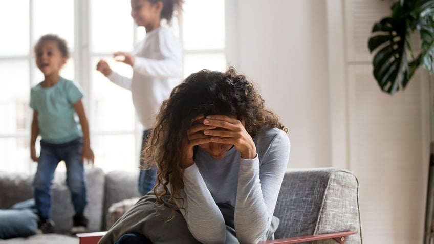 mom stressed out by kids jumping on couch