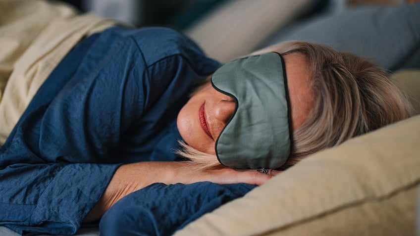 Close up shot of older woman sleeping with her eyes covered with a mask